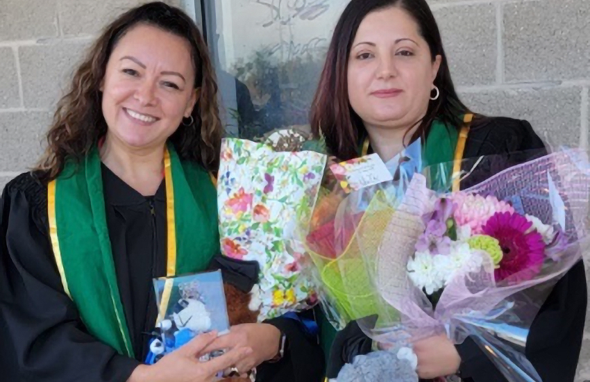 Female students in graduation gowns with flowers and stuffed animals