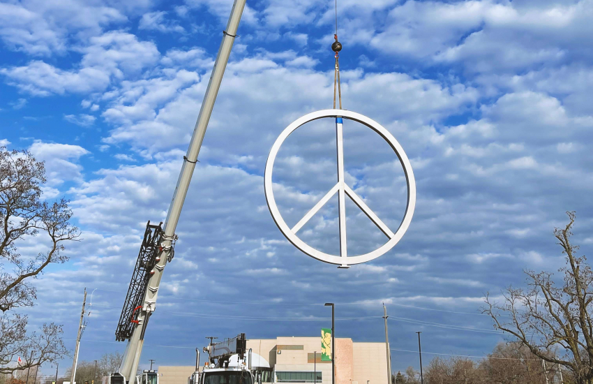 Crane lowering peace symbol into place